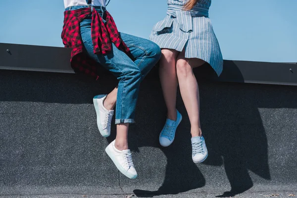Cropped image of two stylish female friends sitting at rooftop — Stock Photo