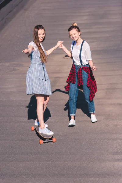 Vista elevata della donna che insegna al suo amico femminile a cavalcare sullo skateboard sul tetto — Foto stock
