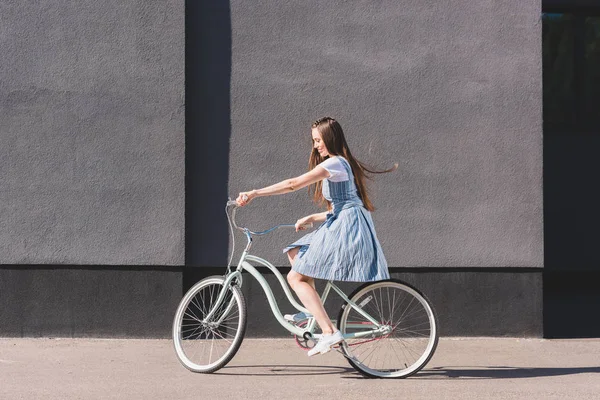 Вид сбоку на молодую счастливую женщину, едущую на велосипеде — стоковое фото