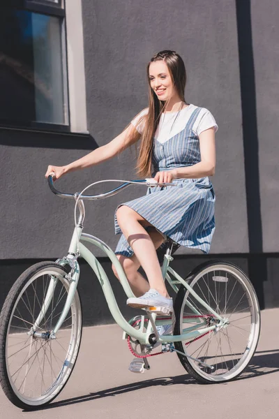 Вид спереду молода усміхнена жінка їде на велосипеді — стокове фото