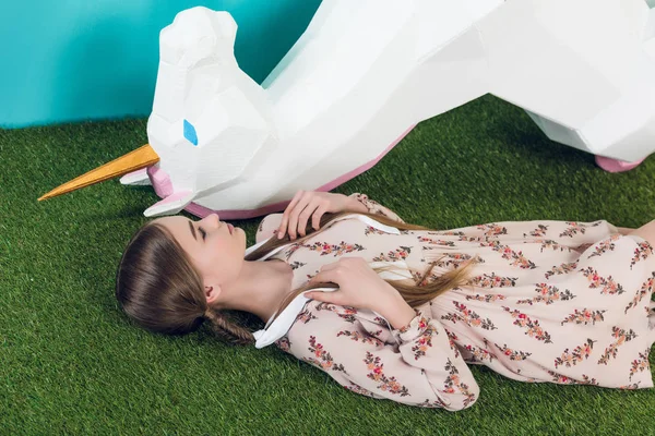 Красива дівчина-підліток лежить з великим білим єдинорогом — стокове фото