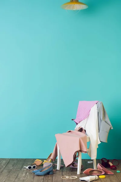 Habitación desordenada con ropa de moda y zapatos en la silla - foto de stock