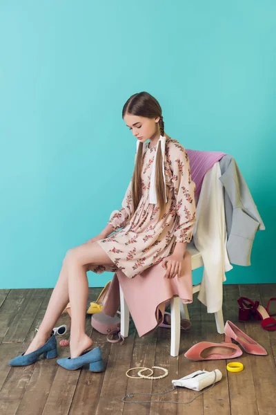 Attraente giovane ragazza seduta sulla sedia con disordine sul pavimento — Foto stock