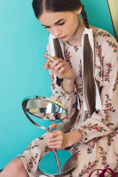 Beautiful teen girl applying lipstick with mirror — Stock Photo