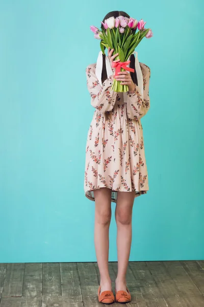 Stylish girl in summer dress holding tulips, on blue — Stock Photo