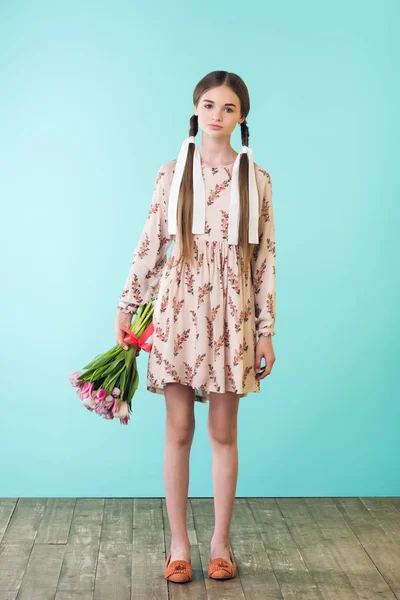 Modisches Mädchen mit Zöpfen im Sommerkleid mit Tulpen, auf Türkis — Stockfoto