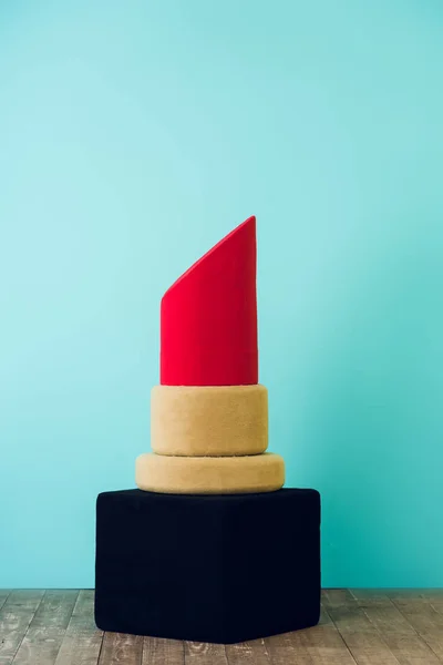 Big red lipstick standing on floor near blue wall — Stock Photo