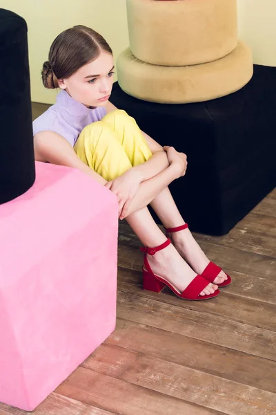 Fashionable teen girl sitting near big nail polish and lipstick — Stock Photo