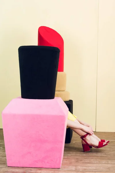 Partial view of girl sitting near big nail polish and lipstick — Stock Photo