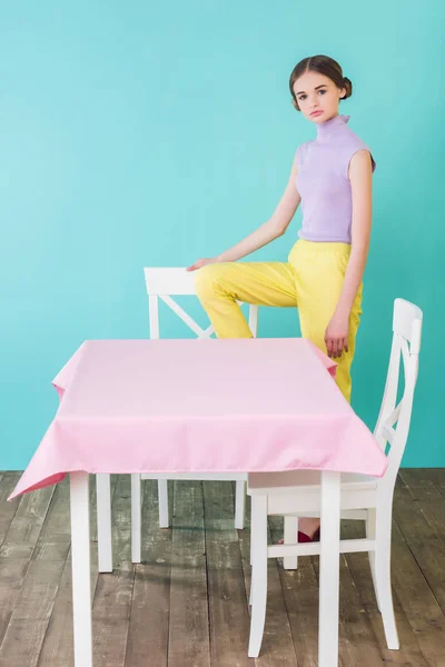 Jeune fille à la mode posant à la table et chaises dans la salle à manger — Photo de stock