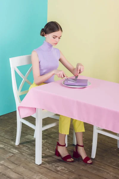 Chica joven con libro en plato en el comedor, concepto de conocimiento - foto de stock