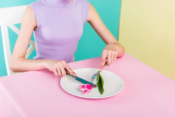 Cropped view of girl on diet eating pink tulip flower — Stock Photo