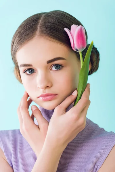 Portrait of attractive teen girl with pink tulip flower, isolated on turquoise — Stock Photo