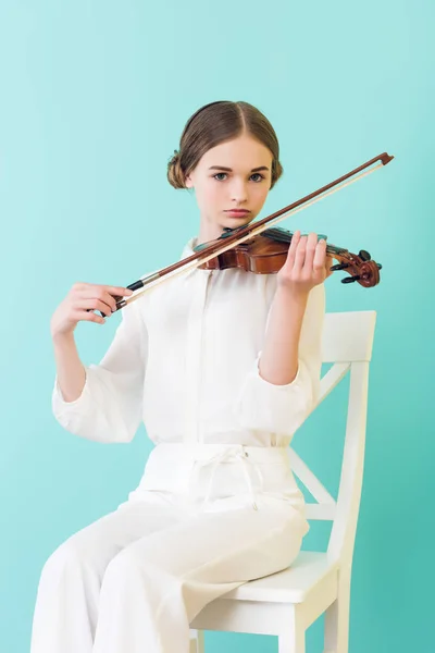 Adolescent fille jouer du violon et assis sur chaise, isolé sur turquoise — Photo de stock