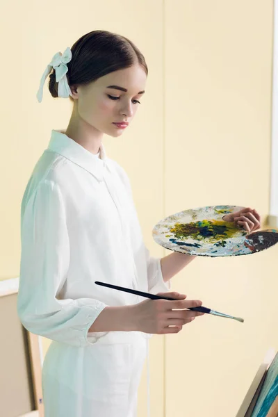 Fashionable teenager painting with brush and palette — Stock Photo