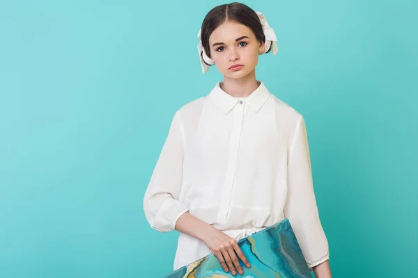 Beautiful female teenager in white outfit holding oil painting, isolated on turquoise — Stock Photo