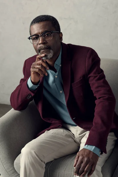 Handsome mature thoughtful african american man sitting in armchair — Stock Photo