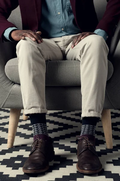 Cropped view of fashionable afro man sitting in armchair — Stock Photo