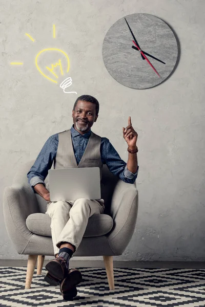 Исполнительный африканский американский бизнесмен с ноутбуком, имеющий идею и указывая вверх, с лампочкой знак — стоковое фото