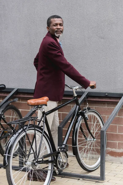 Homem americano africano de meia idade com bicicleta no estacionamento para bicicletas — Fotografia de Stock