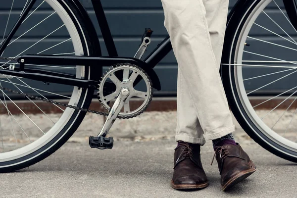 Частковий вид людини в білих штанях позує біля велосипеда — стокове фото