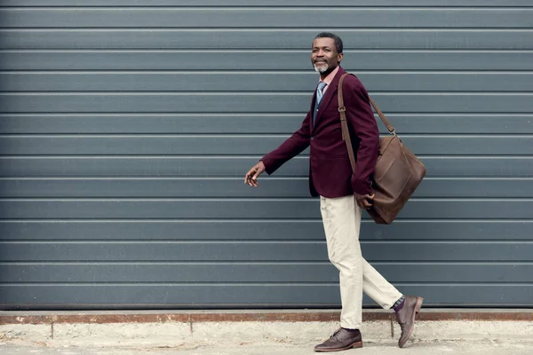 Uomo afroamericano alla moda in giacca bordeaux con borsa in pelle — Foto stock