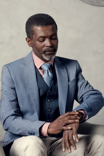 Hombre de negocios afroamericano de mediana edad mirando el reloj - foto de stock