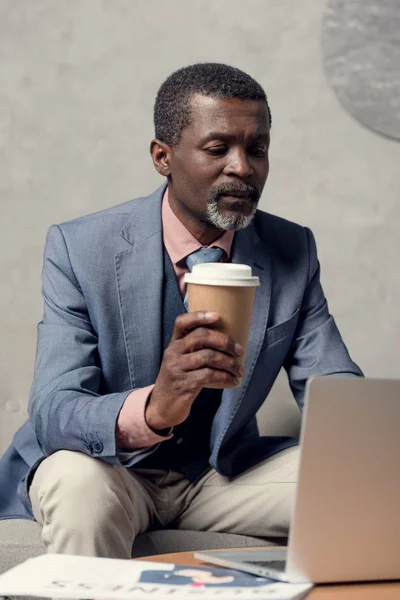 Homem de negócios americano africano de meia idade em jaqueta azul com café e laptop — Fotografia de Stock
