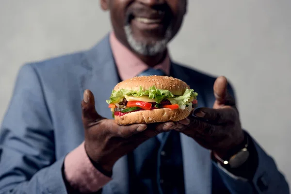 Vista recortada del hombre afroamericano con hamburguesa - foto de stock