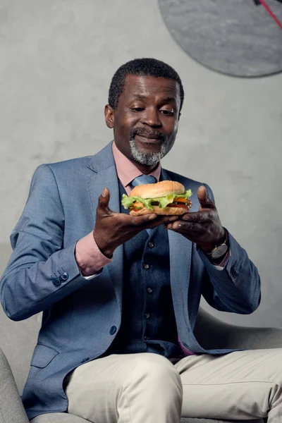 Glücklicher afrikanisch-amerikanischer Geschäftsmann mittleren Alters mit Hamburger — Stockfoto