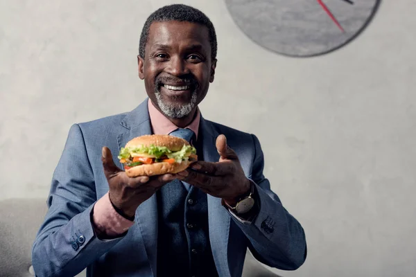 Alegre mediana edad afroamericano hombre con hamburguesa - foto de stock