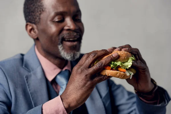 Hombre afroamericano de mediana edad con hamburguesa - foto de stock