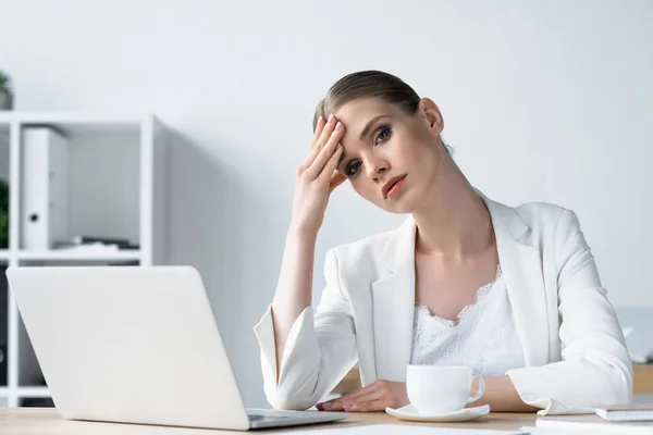 Overworked young businesswoman sitting at workplace in office — Stock Photo