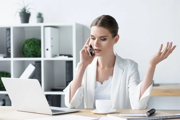 Впевнена молода бізнес-леді розмовляє по телефону в офісі — стокове фото