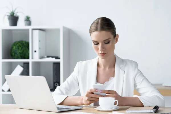 Schöne junge Geschäftsfrau nutzt Smartphone im Büro — Stockfoto