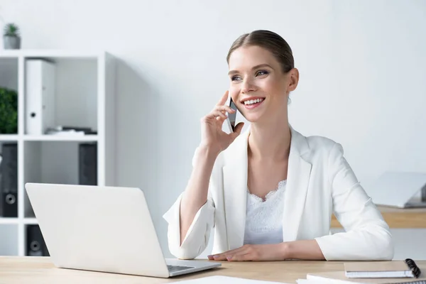 Feliz joven mujer de negocios hablando por teléfono en la oficina - foto de stock