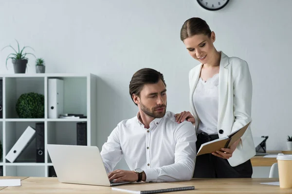 Young beautiful secretary showing notes to boss at office — Stock Photo