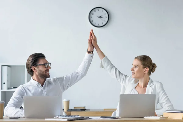 Happy successful managers working with laptops together at office and giving high five — Stock Photo