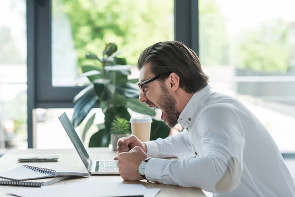 Вид збожеволілий молодий бізнесмен кричить на ноутбук в офісі — Stock Photo