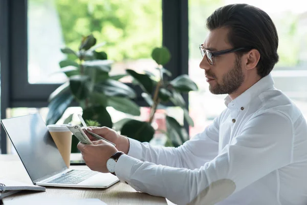 Seitenansicht eines hübschen jungen Geschäftsmannes, der im Büro Bargeld zählt — Stockfoto