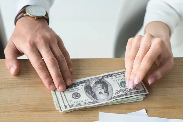 Cropped shot of business partners holding stack of cash on table — Stock Photo