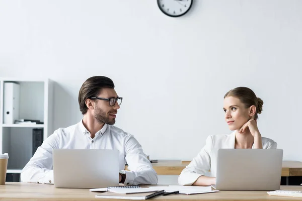 Manager, die im Büro gemeinsam mit Laptops arbeiten und einander anschauen — Stockfoto