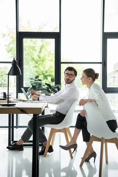 Visão lateral de jovens gerentes atraentes que trabalham juntos no escritório moderno — Fotografia de Stock