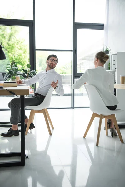 Jovens gerentes felizes conversando no local de trabalho no escritório moderno — Fotografia de Stock