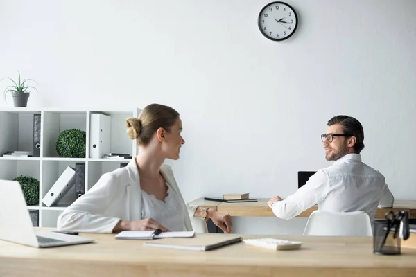 Jóvenes colegas de negocios charlando en el lugar de trabajo en la oficina - foto de stock