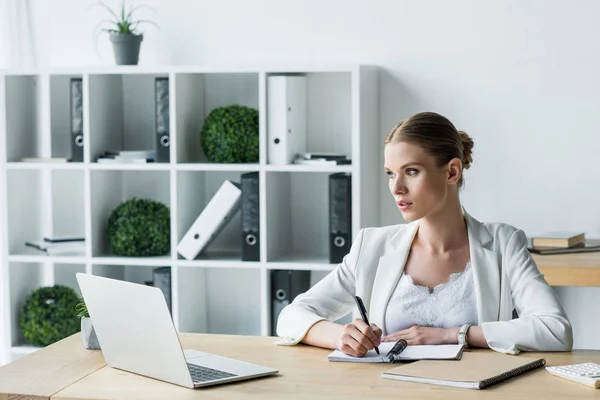 Attraktive junge Geschäftsfrau macht sich während der Arbeit im Büro Notizen — Stockfoto