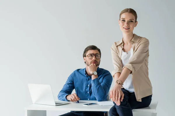 Homme d'affaires amoureux assis sur le lieu de travail et regardant son collègue alors qu'elle est assise sur son bureau isolé sur blanc — Photo de stock