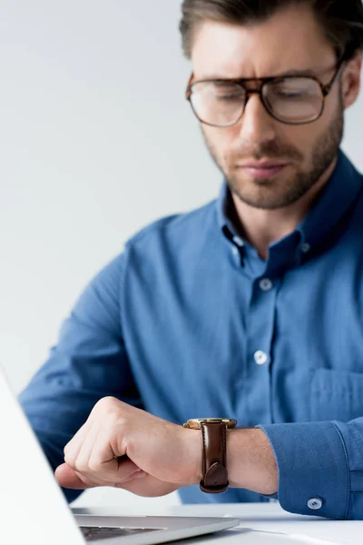 Bello giovane uomo d'affari guardando orologio durante il lavoro isolato su bianco — Foto stock