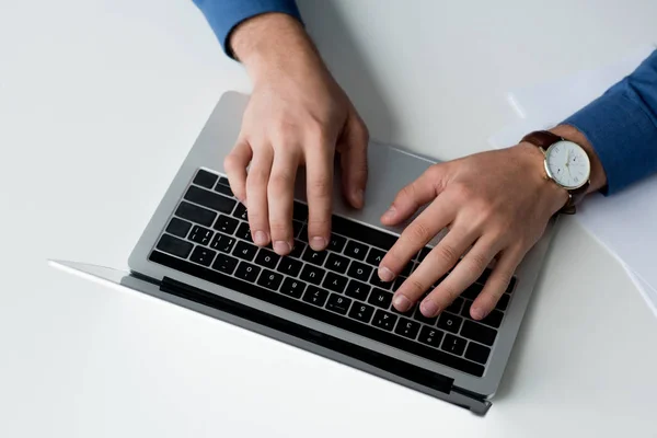 Обрезанный снимок человека, работающего с ноутбуком на белой поверхности — стоковое фото