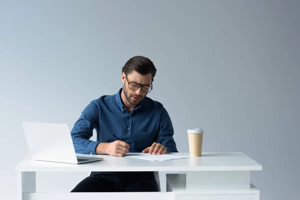 Jovem empresário focado assinando documentos no local de trabalho isolado em branco — Fotografia de Stock